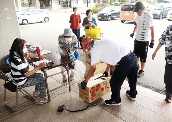 受付に衣類を持ち込む市民(3)