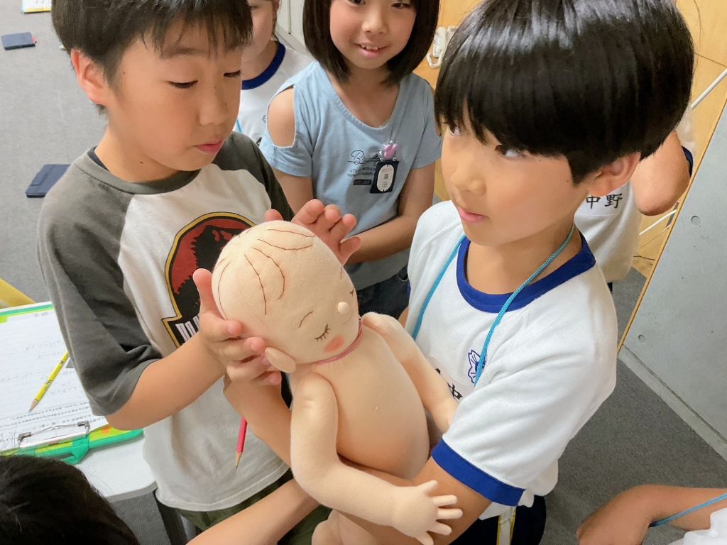 赤ちゃんの人形を抱く小学生